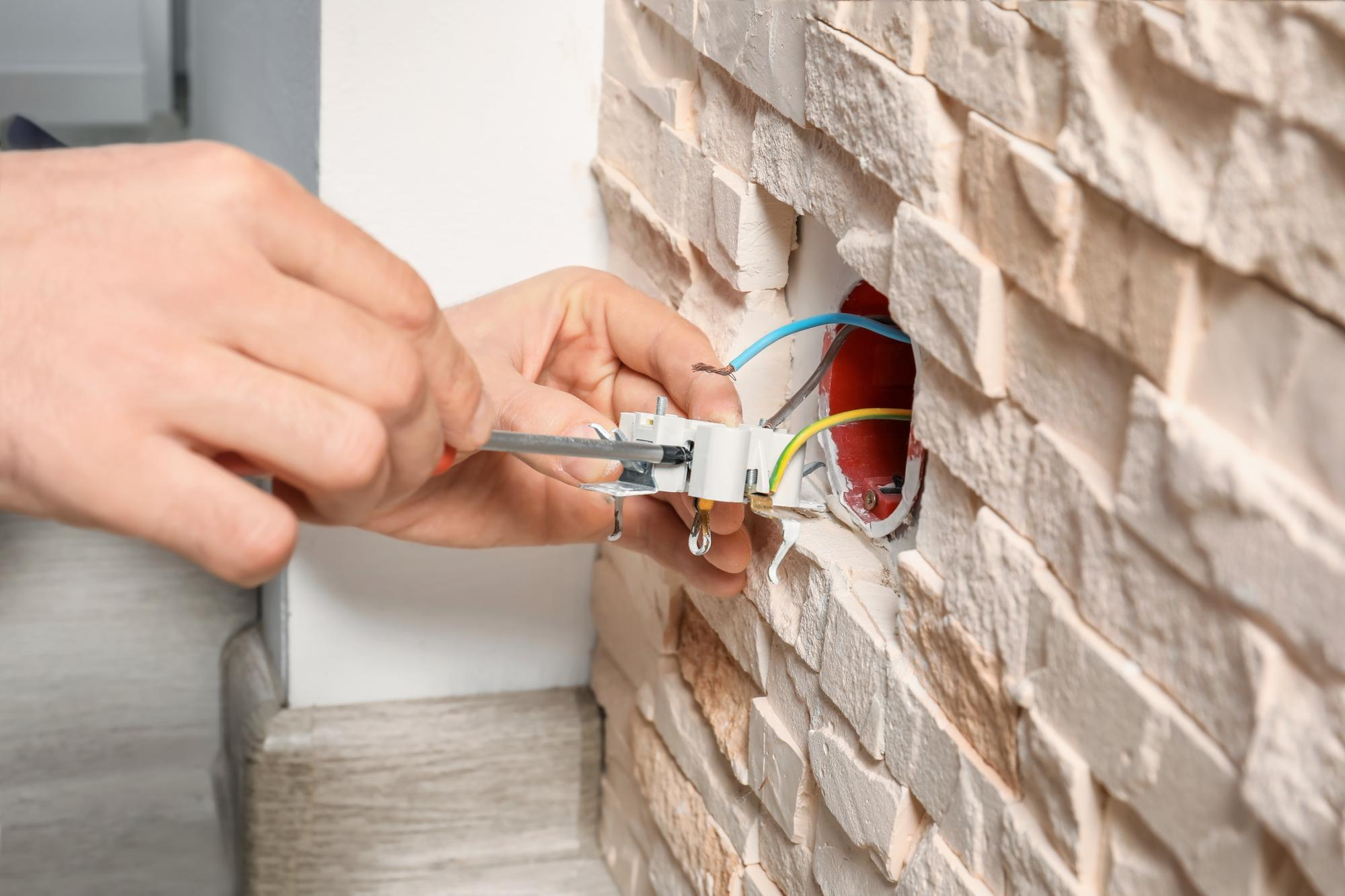 Électricien raccordant une prise murale lors d’une installation électrique