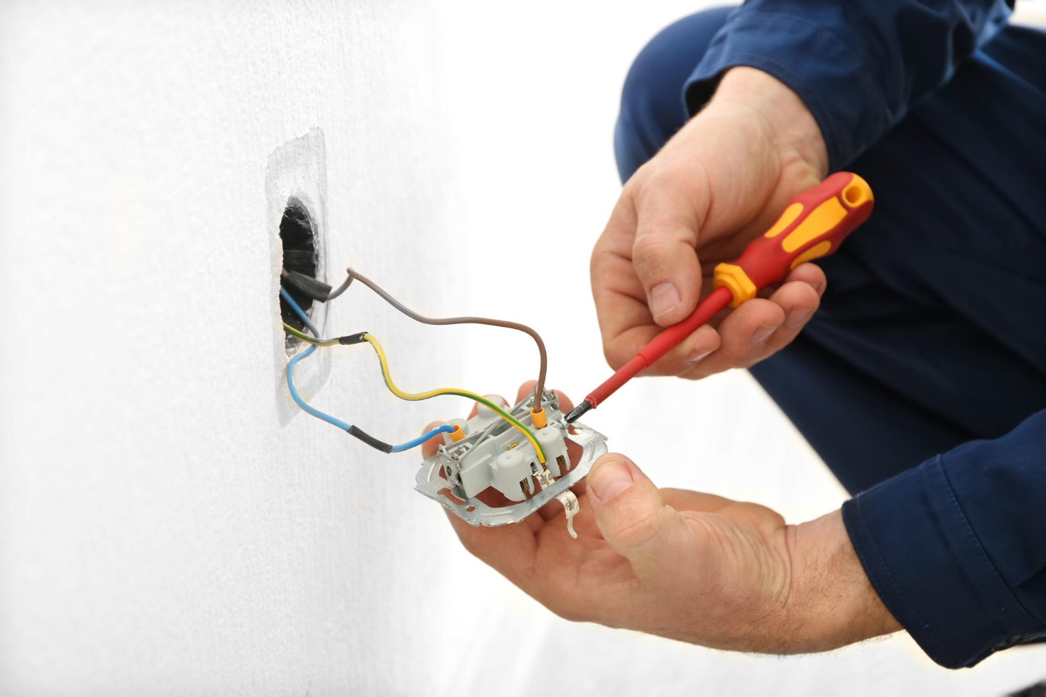 Électricien réparant une prise murale lors d’un dépannage électrique
